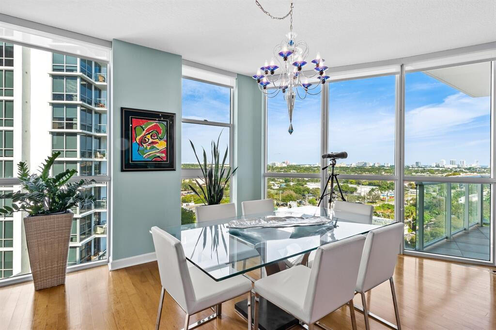 a dining room with furniture a floor to ceiling window and wooden floor