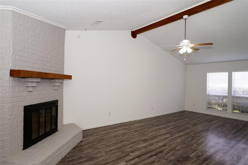 a view of a livingroom with a fireplace a ceiling fan and wooden floor