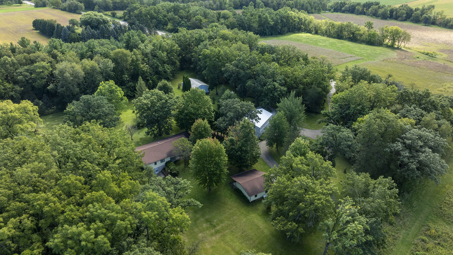 an aerial view of residential house with outdoor space and trees all around