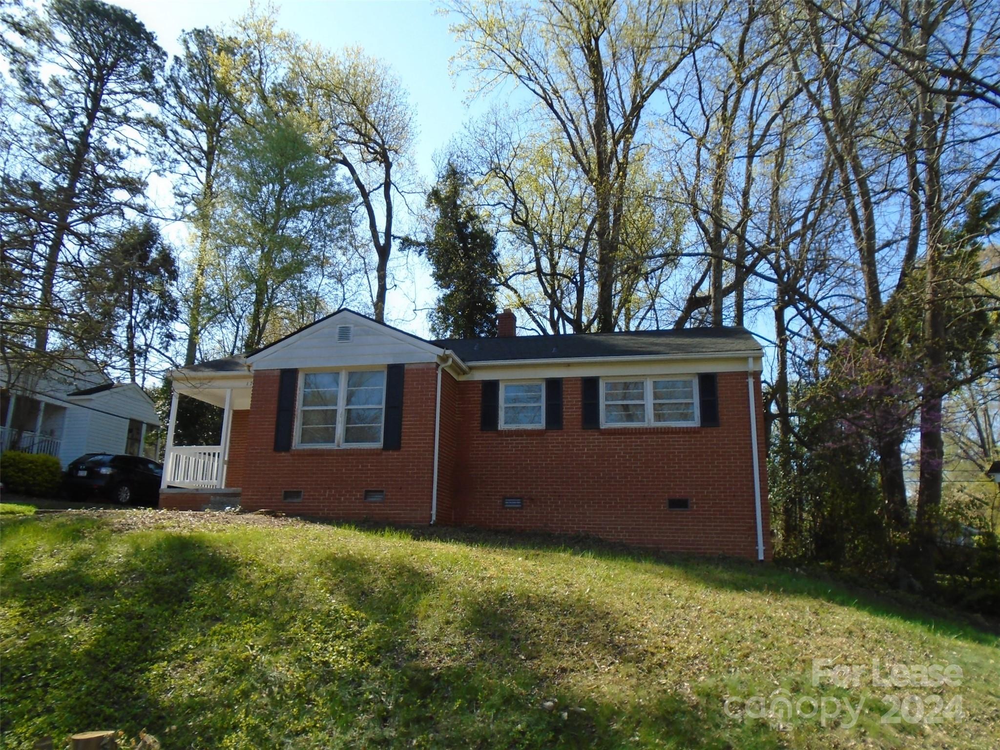 a front view of house with yard and trees all around