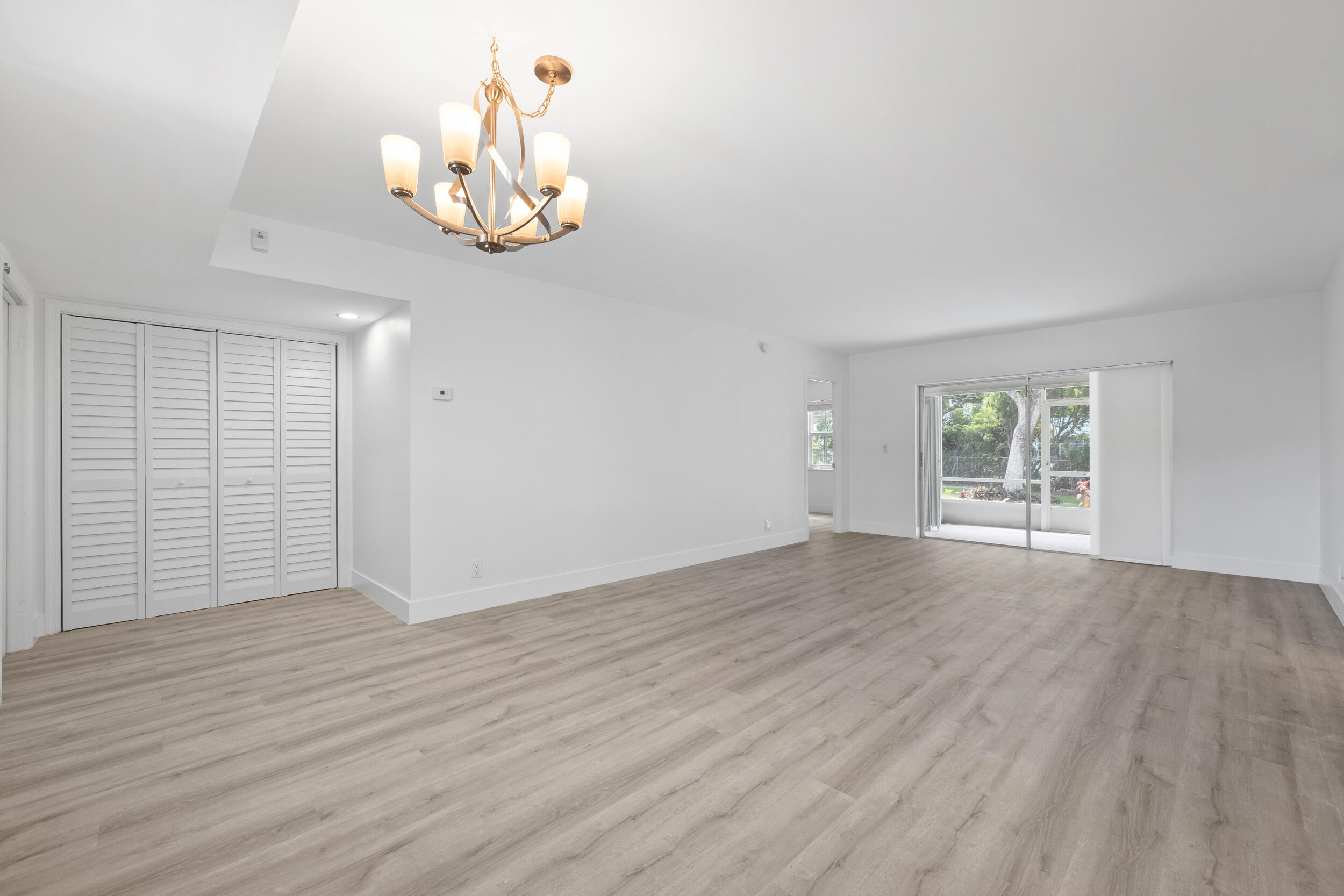 an empty room with wooden floor cabinet and windows