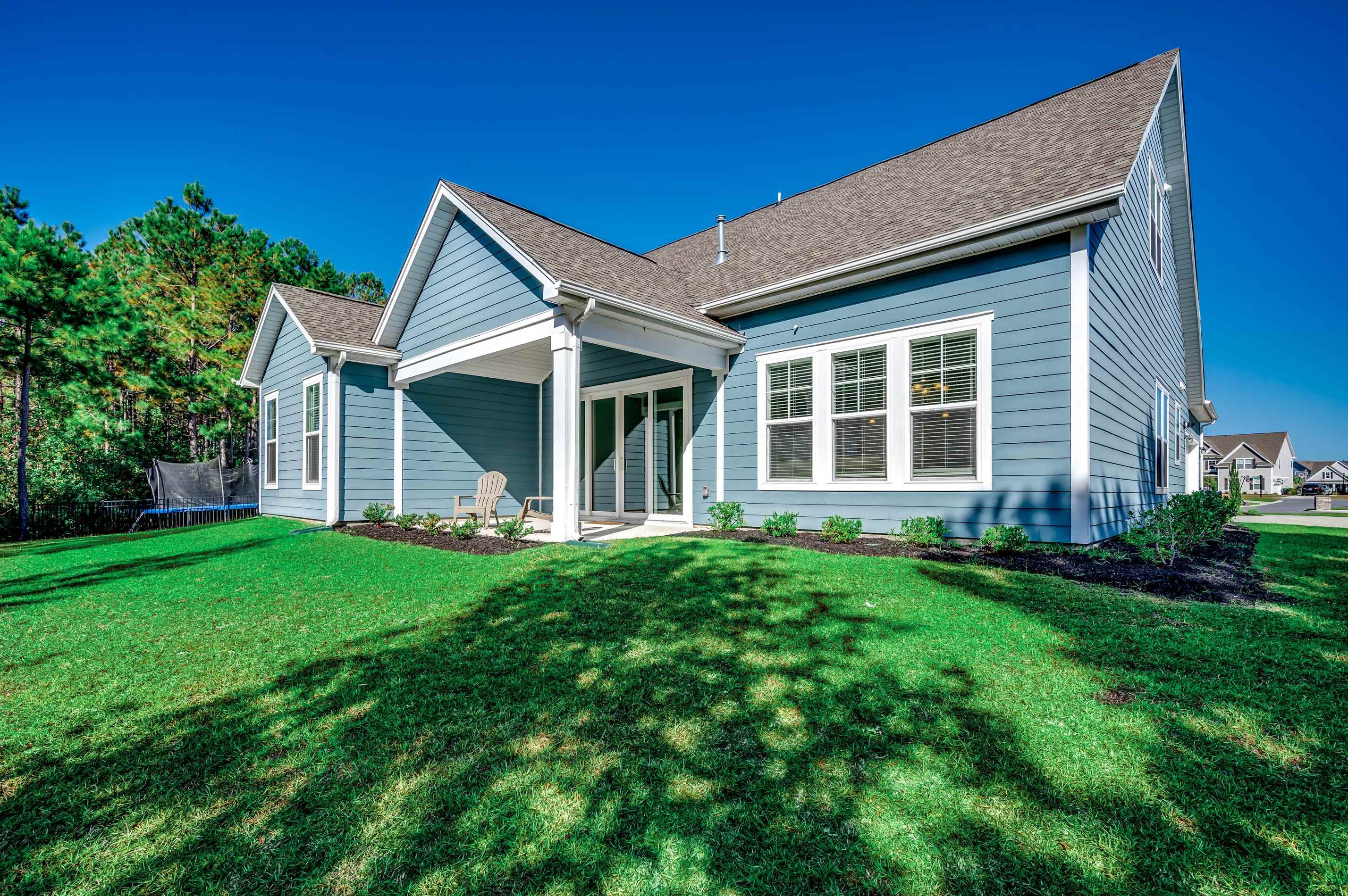 Rear view of property with a lawn and a trampoline