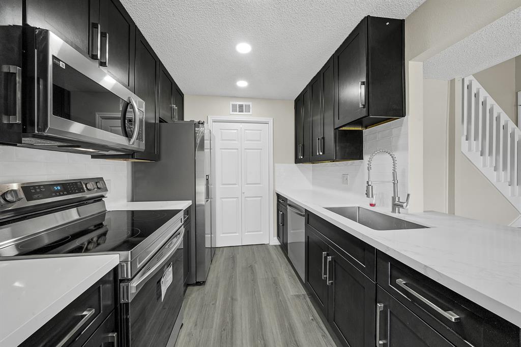 a kitchen with stainless steel appliances sink stove microwave and cabinets