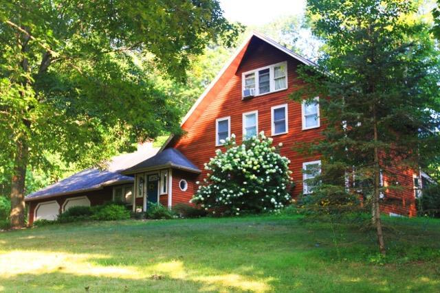 a view of a house with a big yard plants and large trees