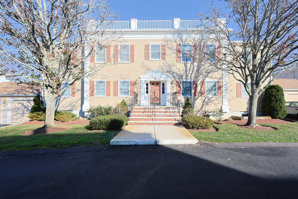 a front view of a house with garden and trees