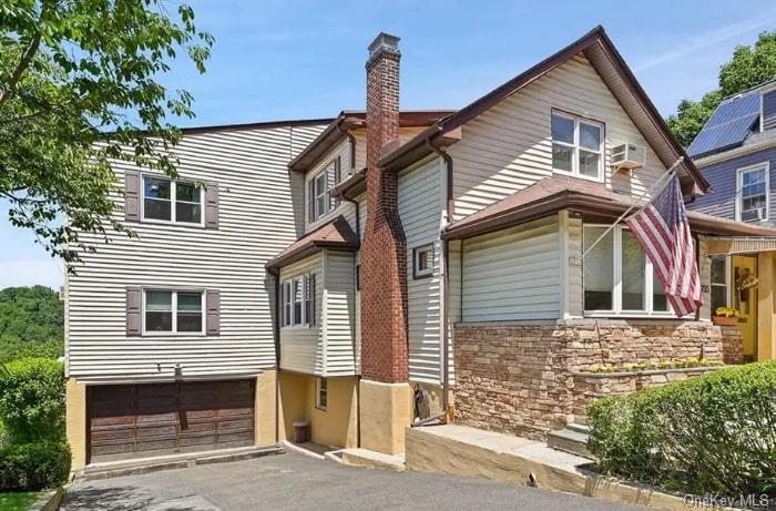 View of front of property featuring a wall unit AC and a garage