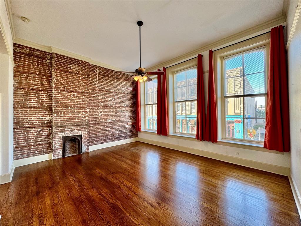 a view of an empty room with wooden floor fireplace and a window