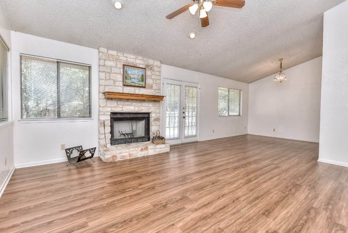 Living room with rock fireplace and hearth, vaulted ceiling, formal dining area, French doors to back porch