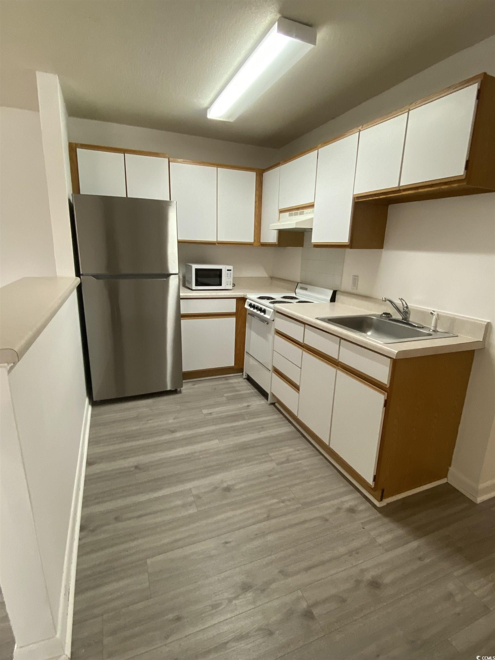 Kitchen featuring white cabinetry, sink, light har