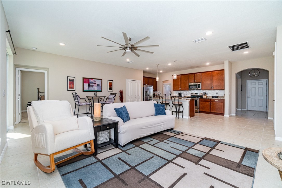 a living room with furniture kitchen view and a chandelier