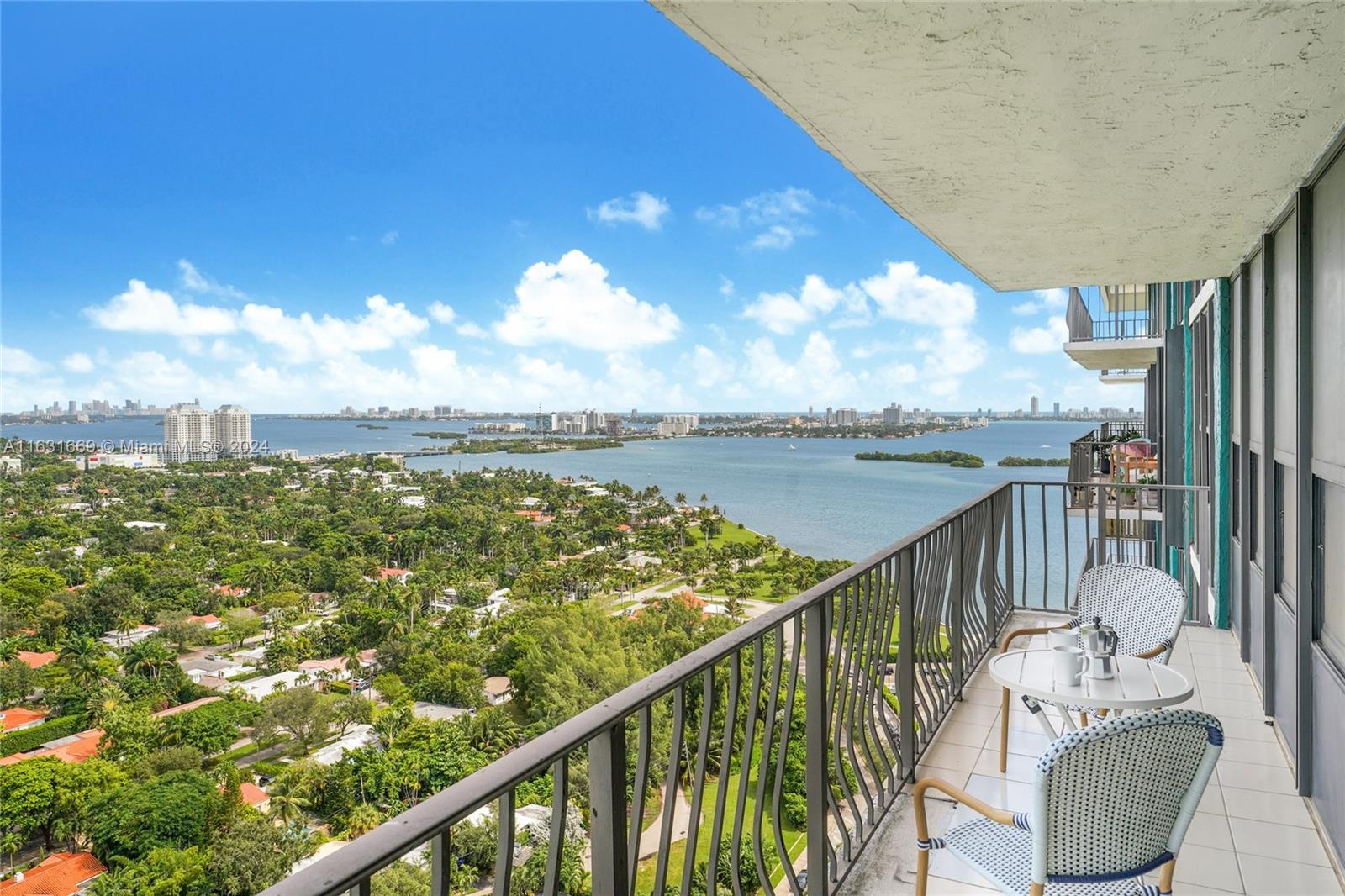 a view of a city from a balcony with outdoor seating