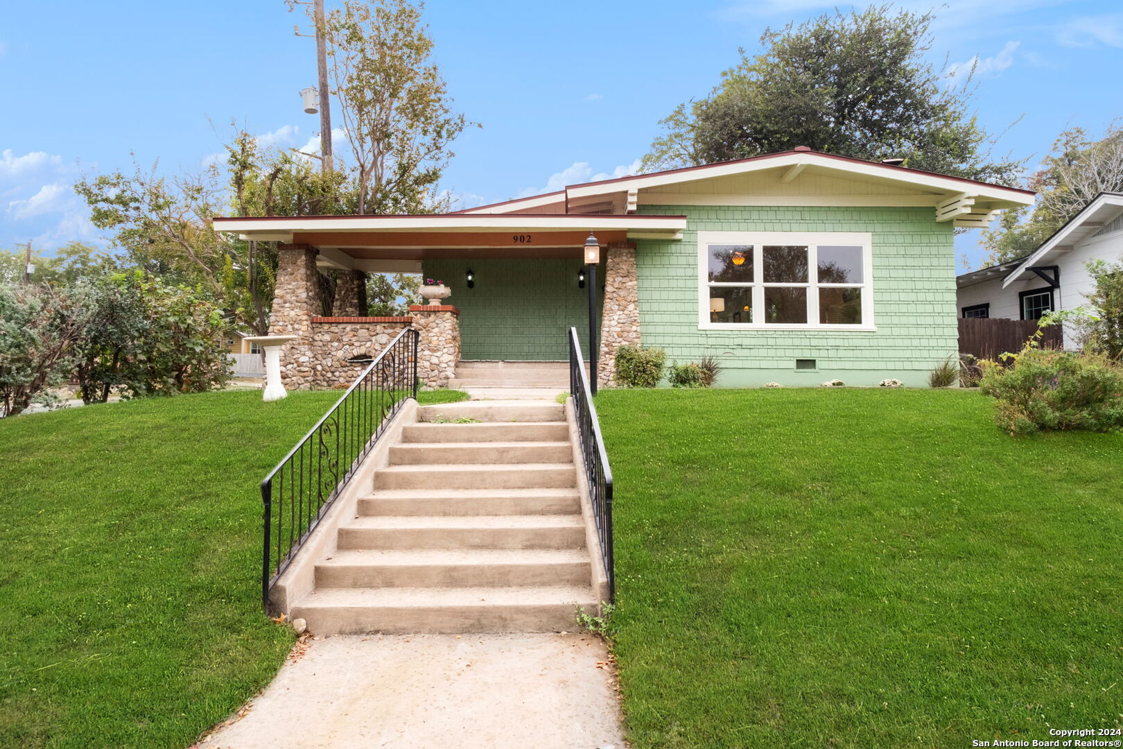 a front view of a house with a yard and potted plants