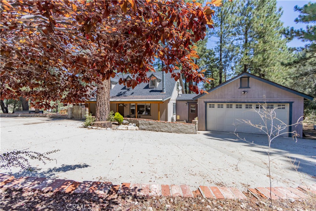 a front view of a house with a yard and a large tree