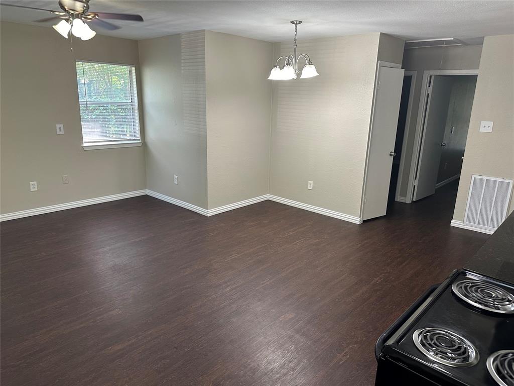 an empty room with wooden floor fan and window