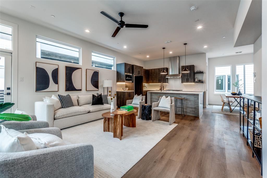 a living room with furniture kitchen area and a wooden floor