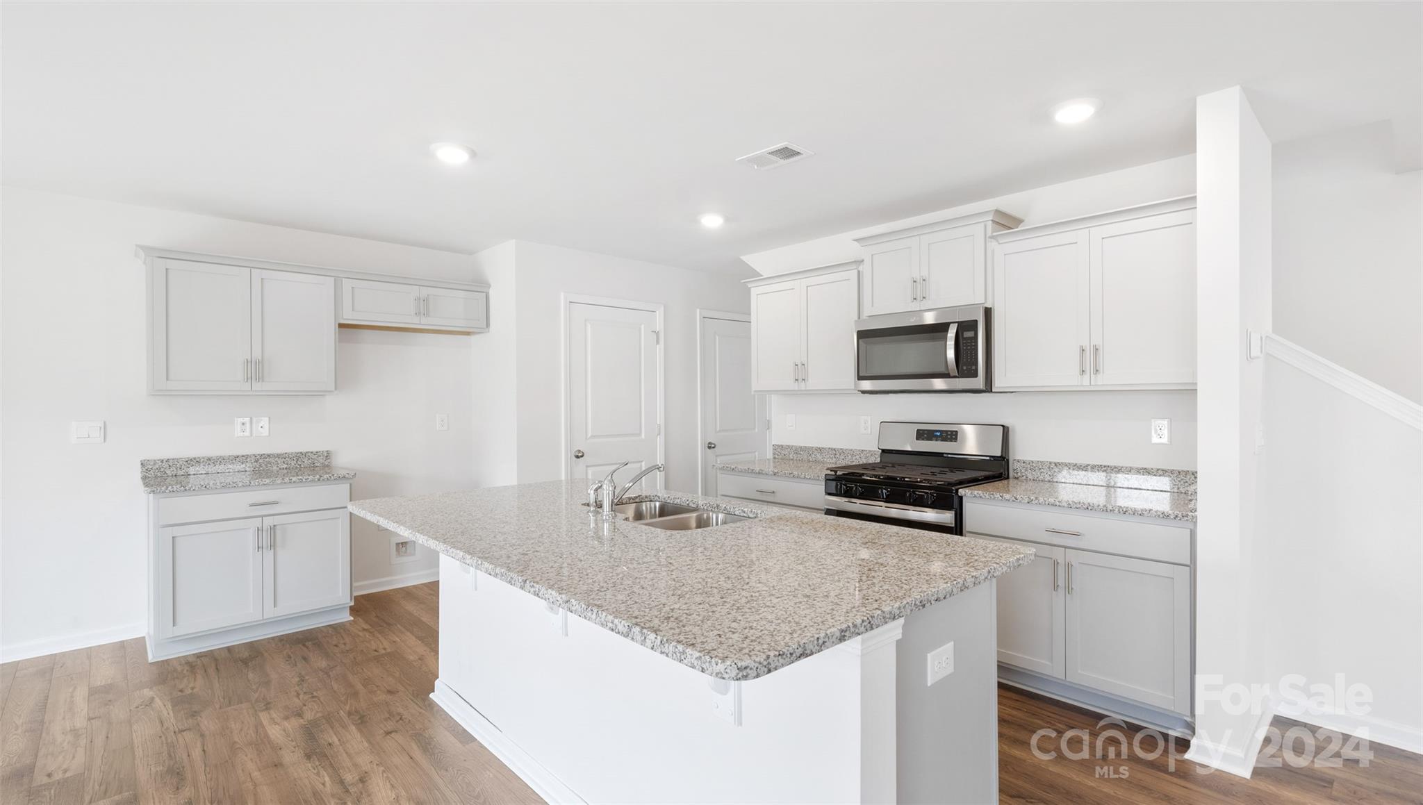 a kitchen with stainless steel appliances granite countertop a sink stove microwave and refrigerator