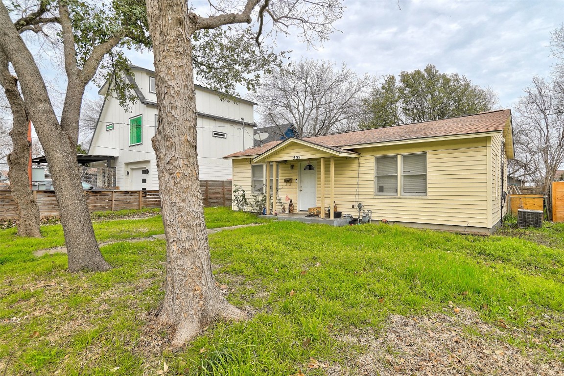 a view of a house with a yard and a large tree