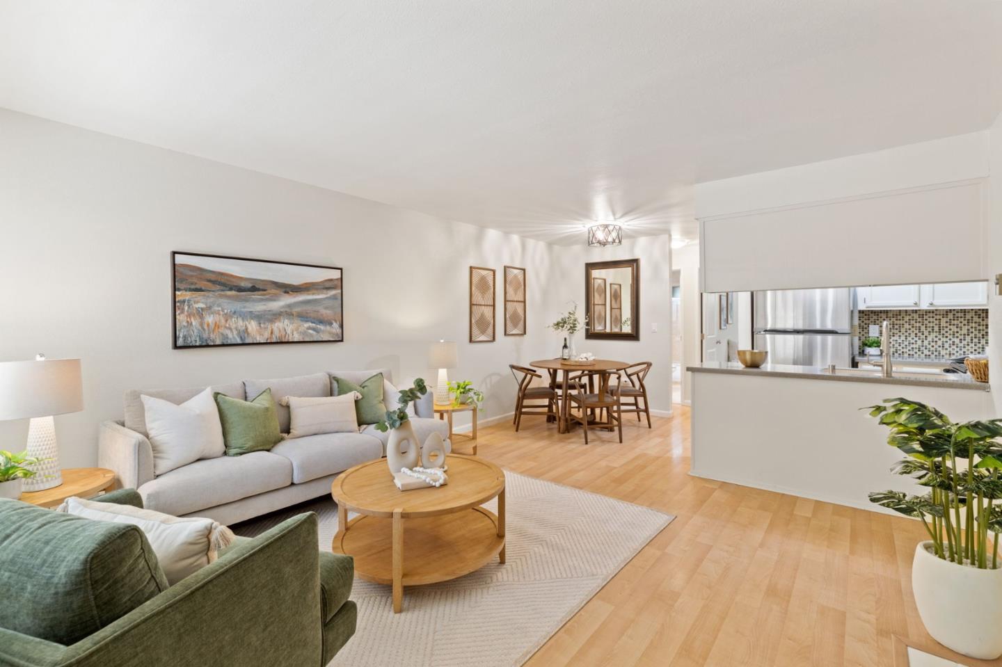 a living room with furniture potted plant and kitchen view