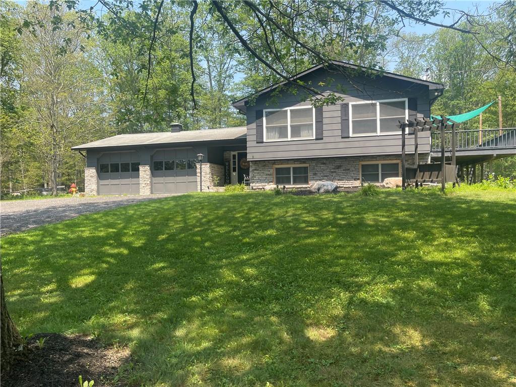 Tri-level home featuring a garage and a front yard