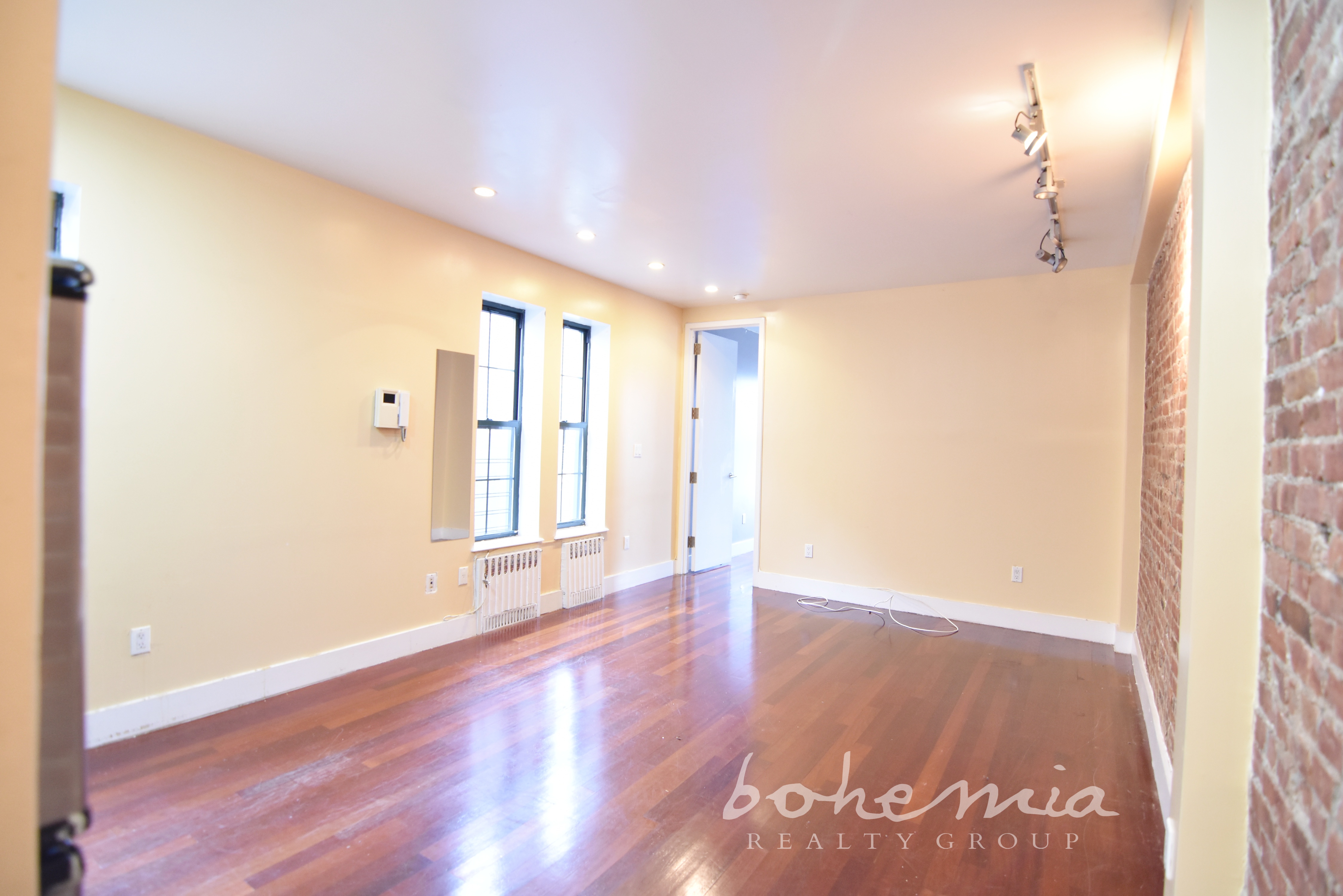 a view of an empty room with wooden floor and a window