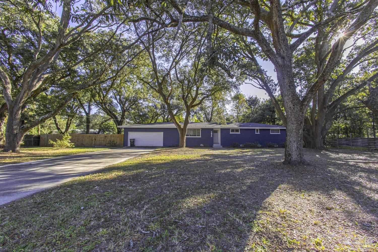 a view of backyard with large trees and wooden fence