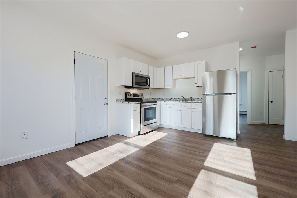 a kitchen with granite countertop a refrigerator and a stove top oven