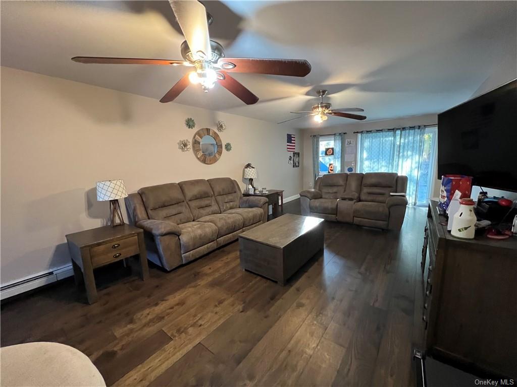 Living room with ceiling fan and dark hardwood / wood-style flooring