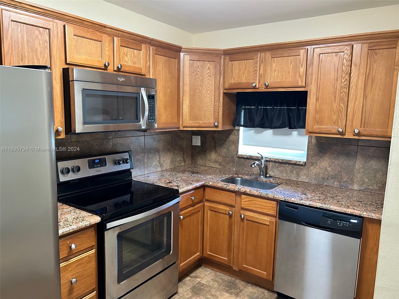 a kitchen with granite countertop a sink stove and microwave