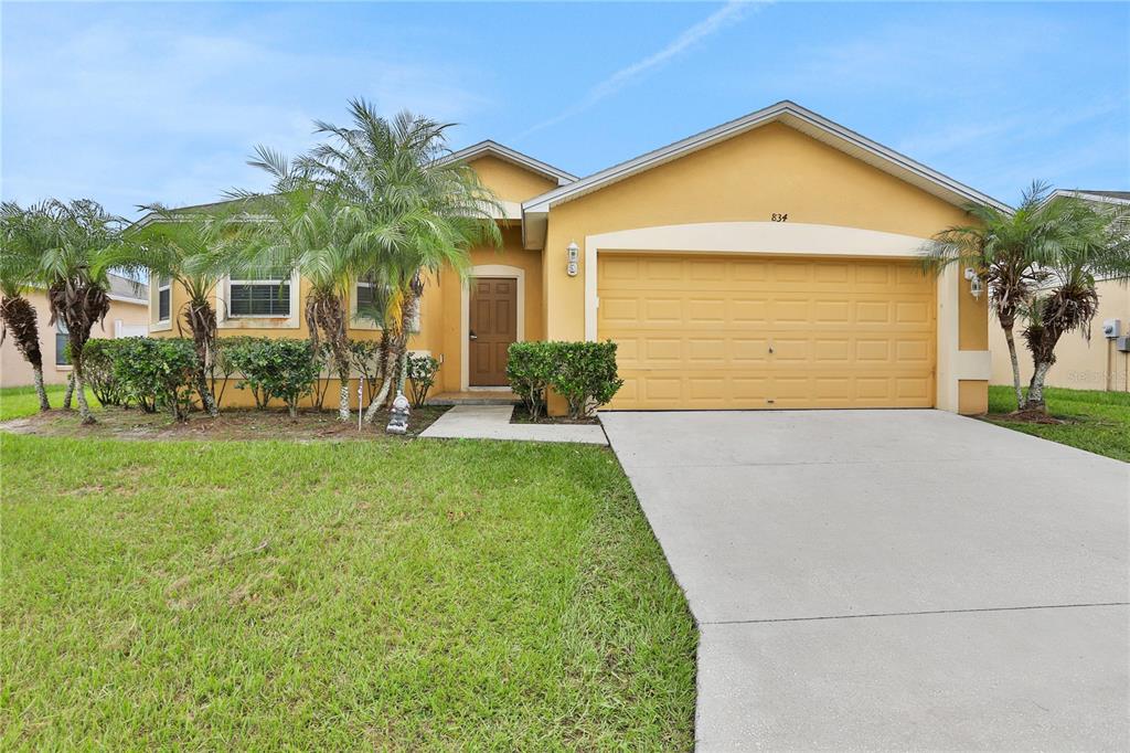 front view of a house with a yard and palm trees