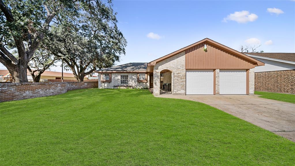 This is a single-story home featuring a well-maintained front lawn with a mature tree, a double garage, and a brick facade. The property offers a welcoming suburban feel with clear skies above.