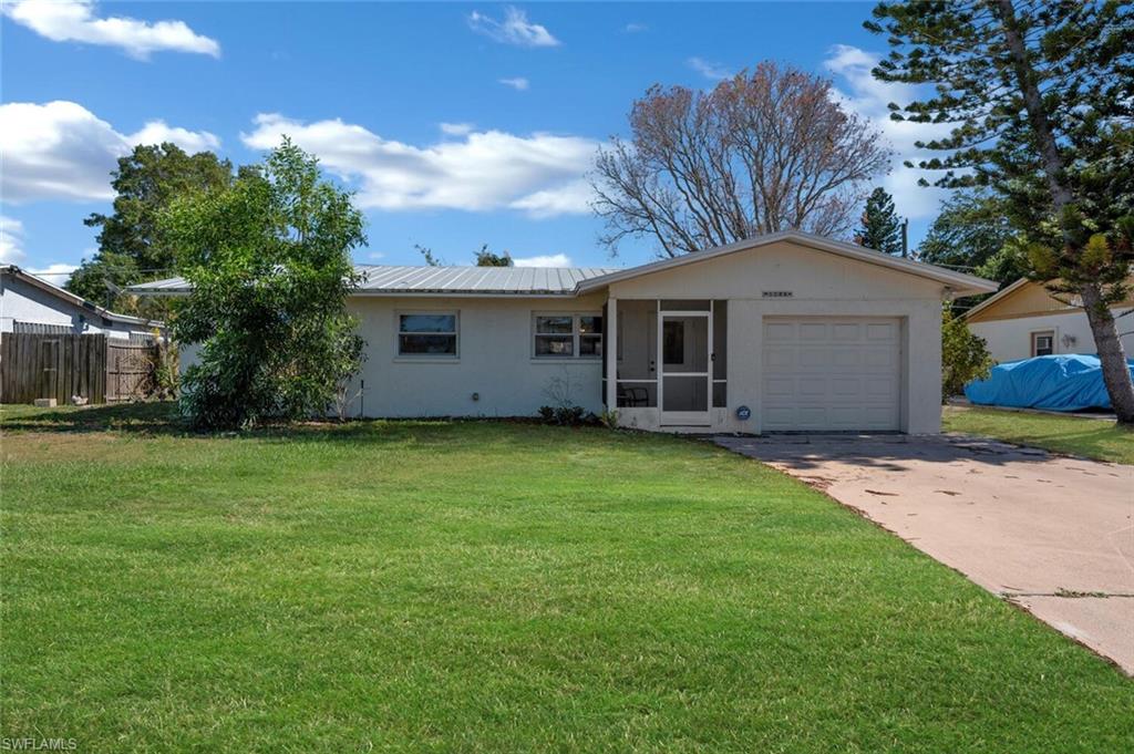 a front view of house with yard and trees in the background