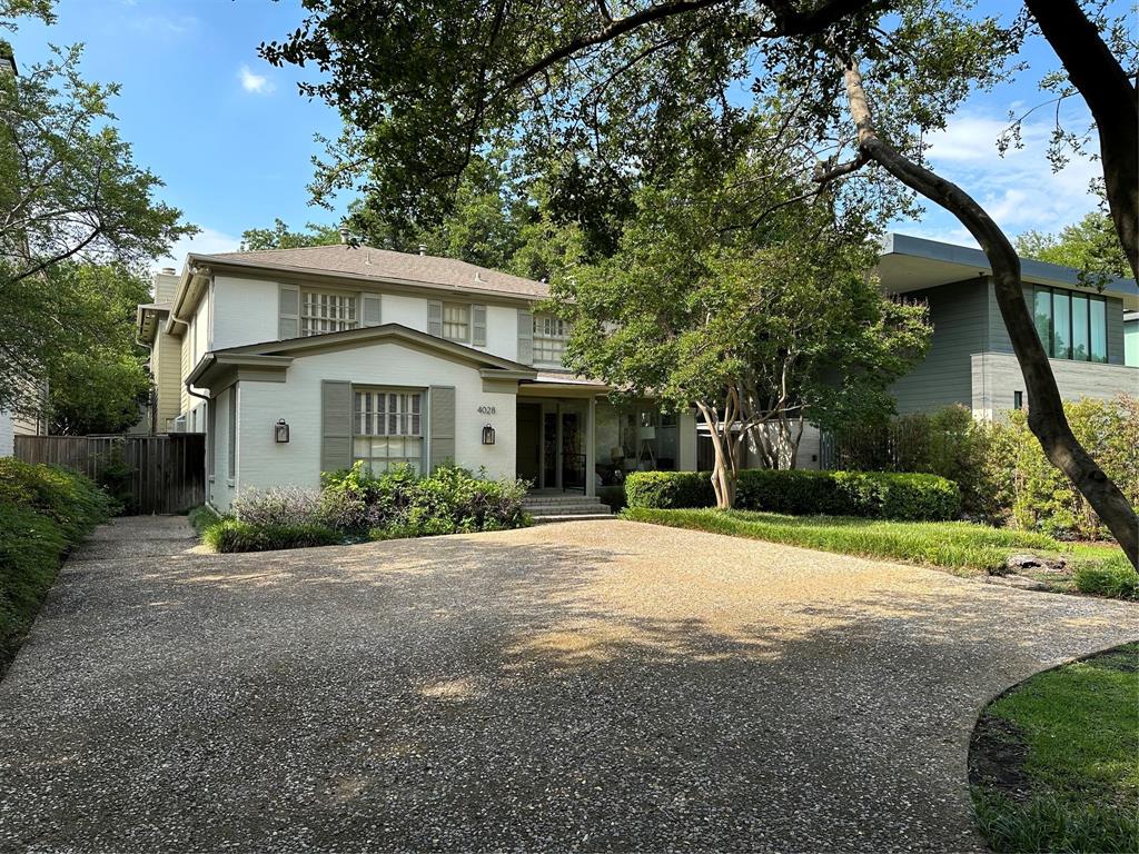 a front view of a house with a garden and trees