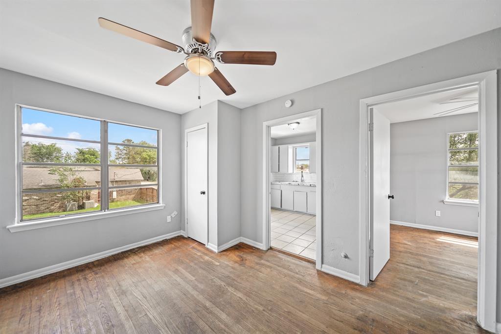 a view of an empty room with a window and wooden floor