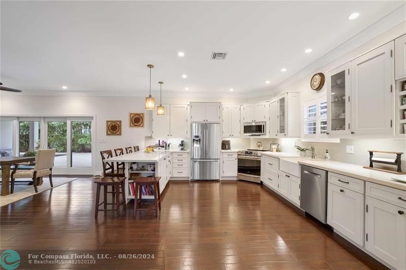 a large white kitchen with lots of counter space a sink and appliances