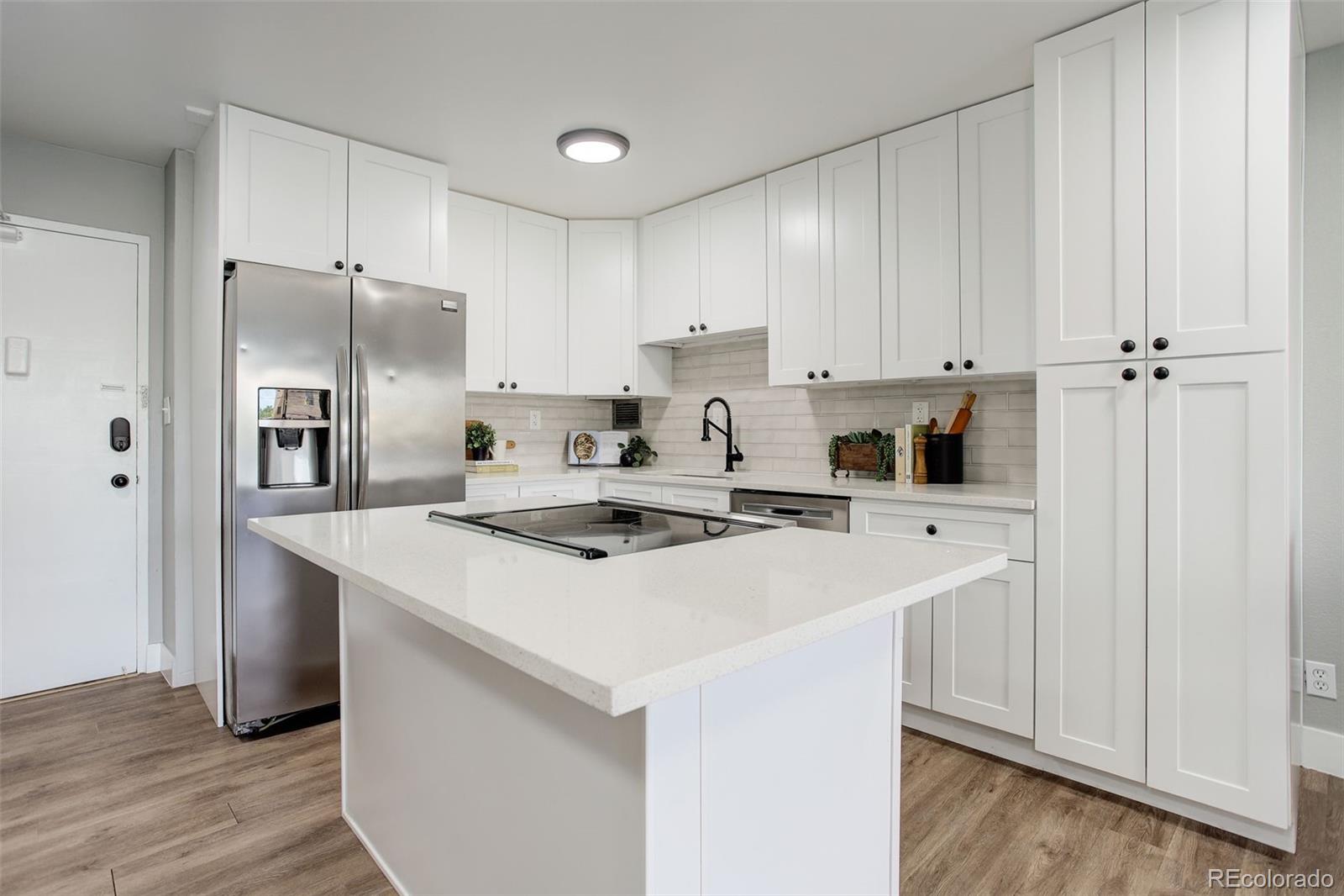 a kitchen with a sink a stove a refrigerator and white cabinets