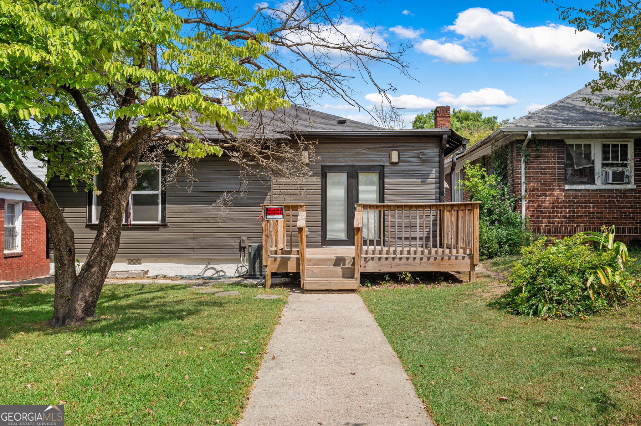 a view of a house with a small yard and a large tree