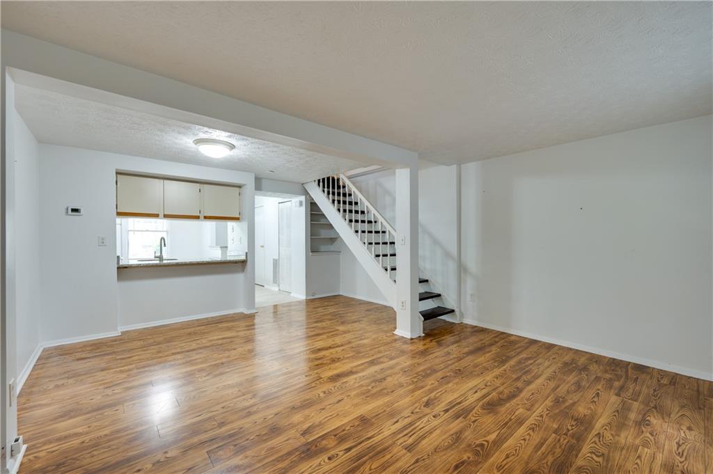 a view of an empty room with wooden floor and stairs