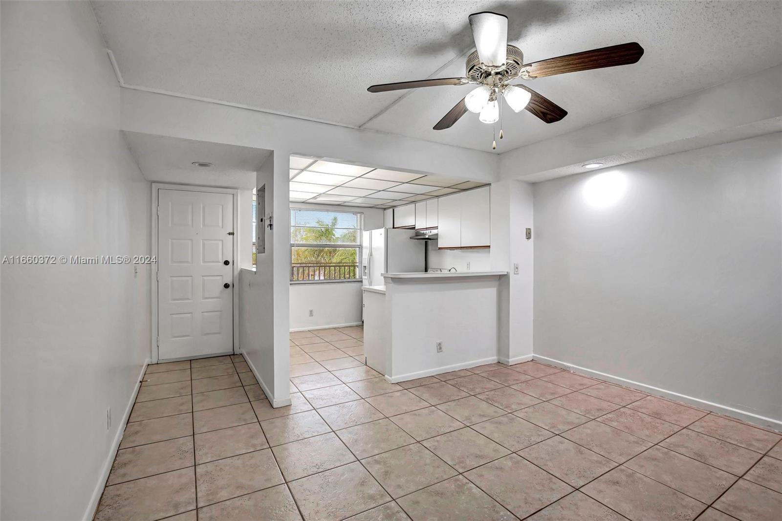 a view of kitchen and empty room with wooden floor