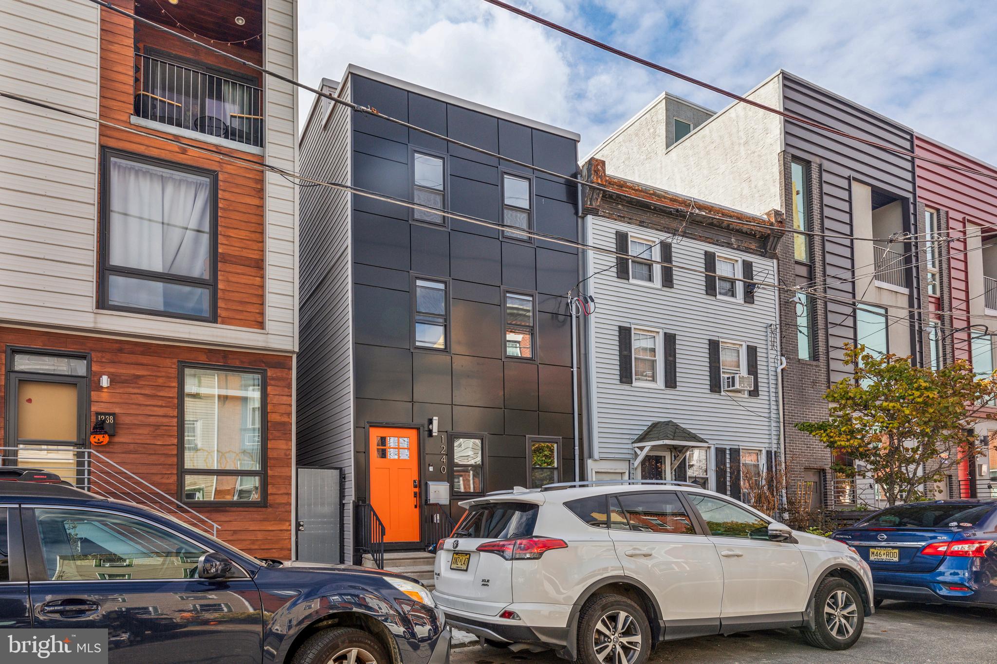 a front view of a residential apartment building with cars parked