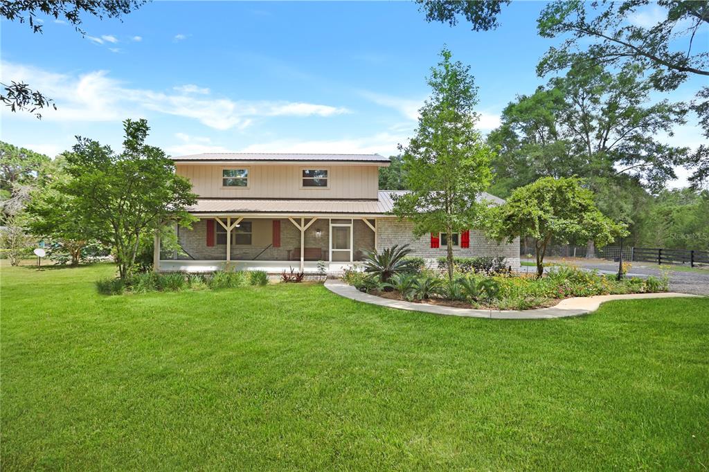 a view of a house with a big yard potted plants and large tree