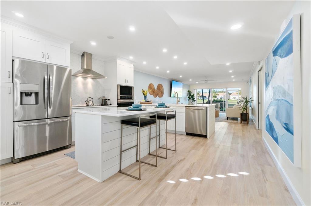 a kitchen with stainless steel appliances kitchen island wooden floors refrigerator and a fireplace