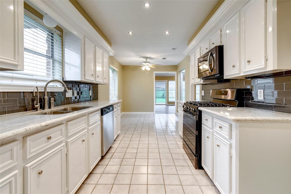 a large kitchen with stainless steel appliances granite countertop lots of white cabinets a stove and a window