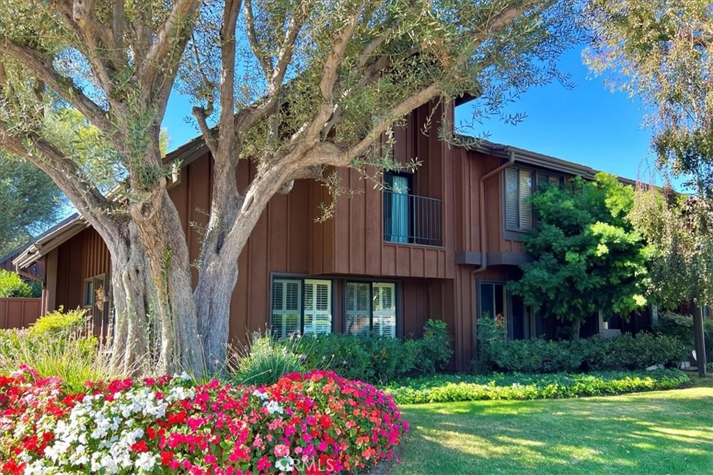 a front view of house and yard with beautiful flowers and green space