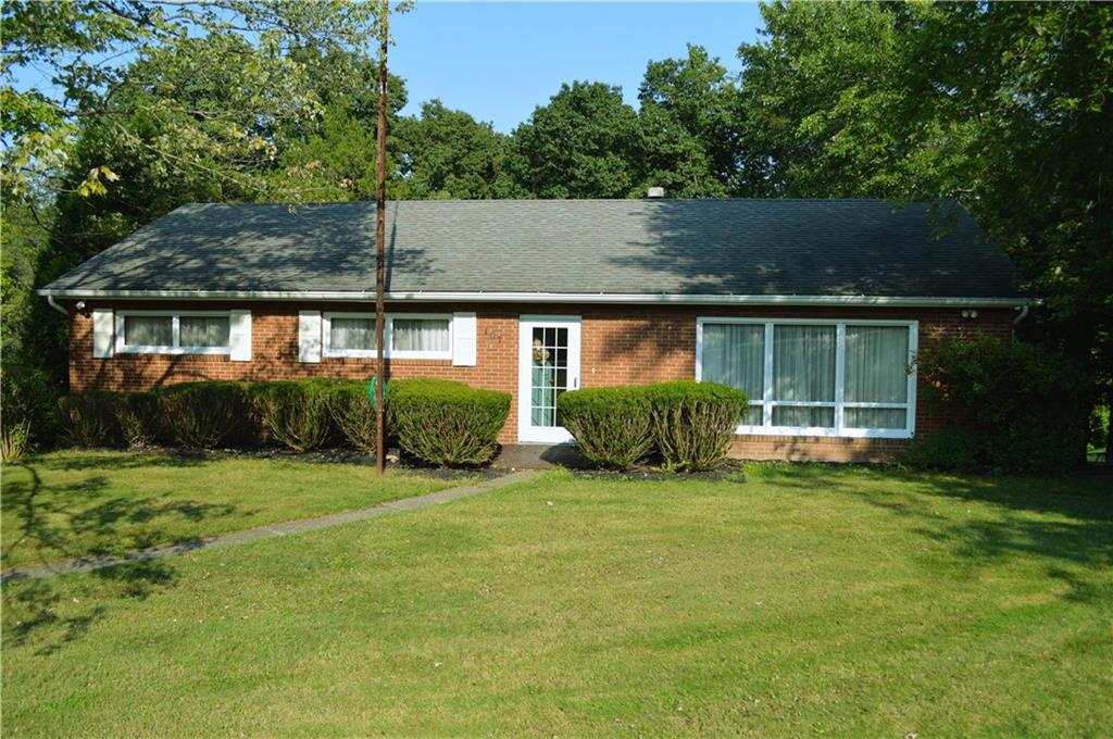 a view of a house next to a big yard and large trees