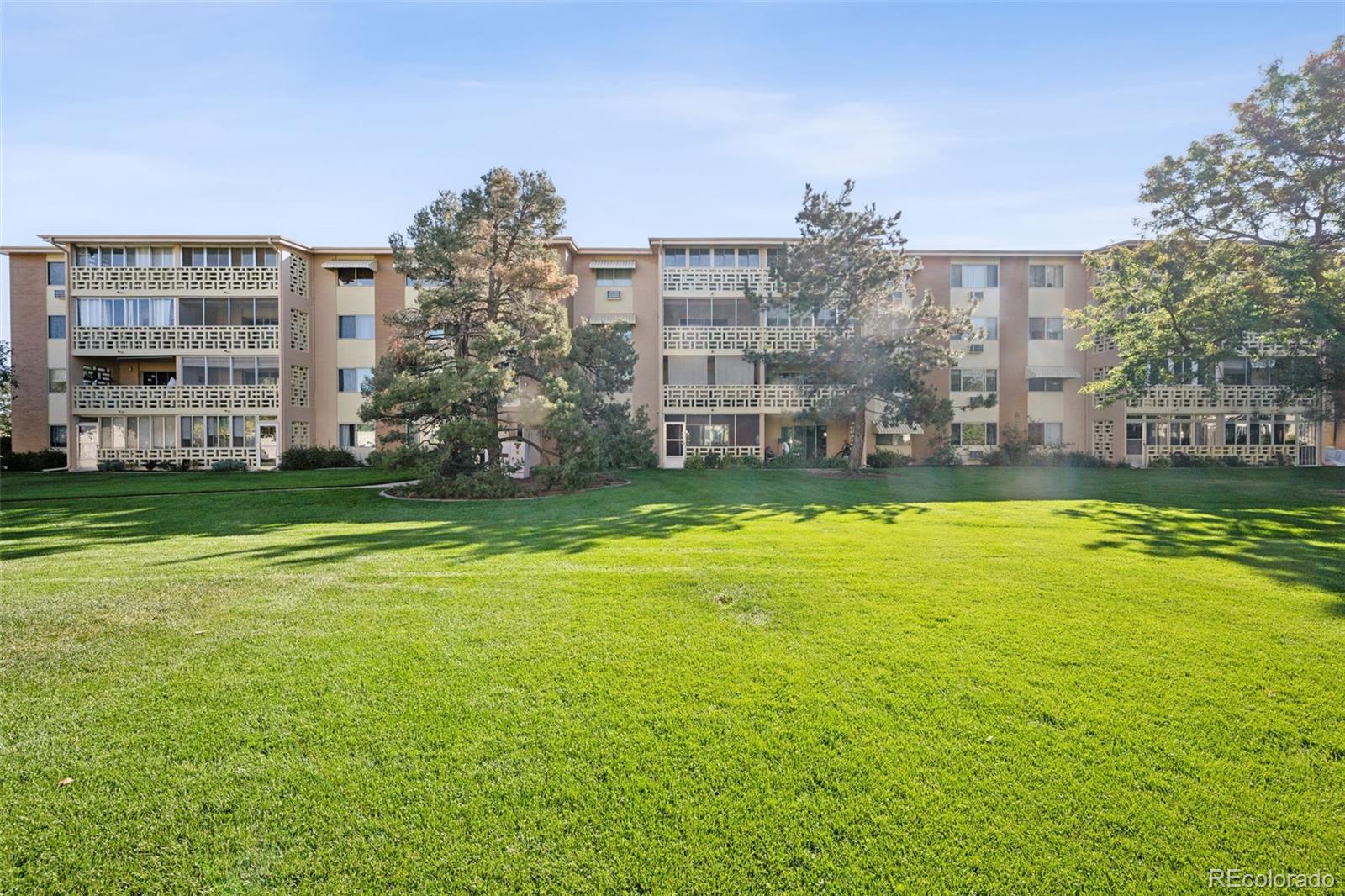 a view of a building with a big yard and large trees