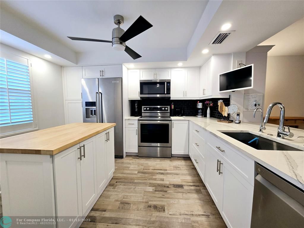 a large kitchen with stainless steel appliances kitchen island granite countertop a stove and a sink