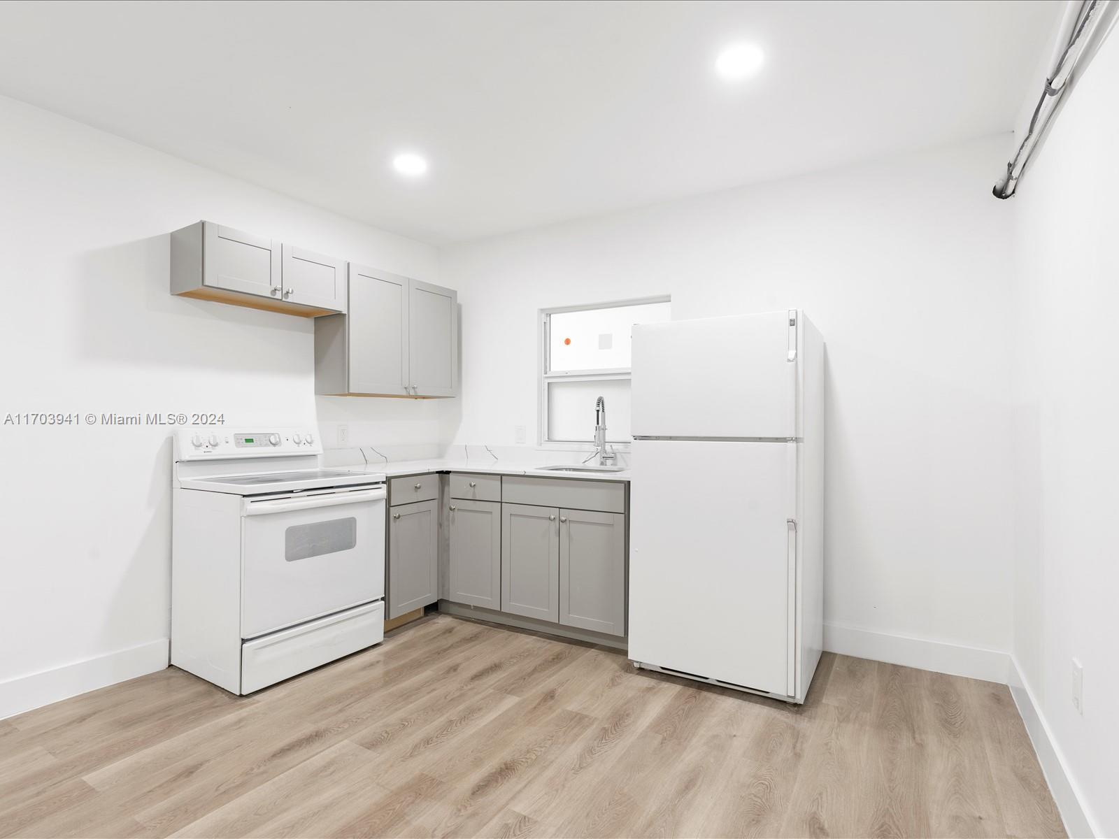 a kitchen with a white cabinets and wooden floor