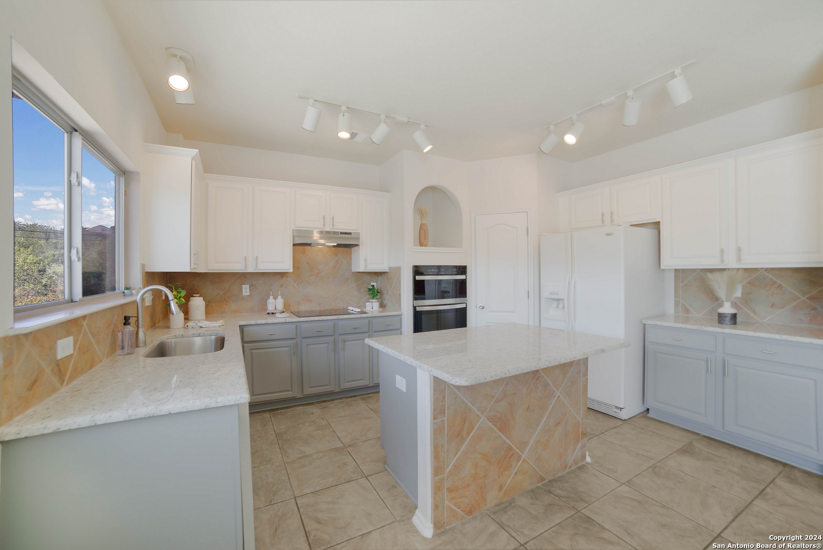 a large kitchen with kitchen island a sink a stove a counter space and cabinets