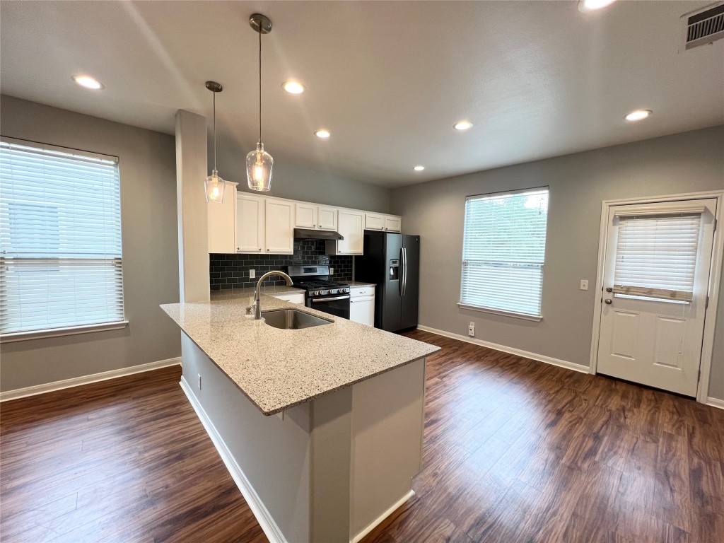 a large kitchen with a center island wooden floor and stainless steel appliances