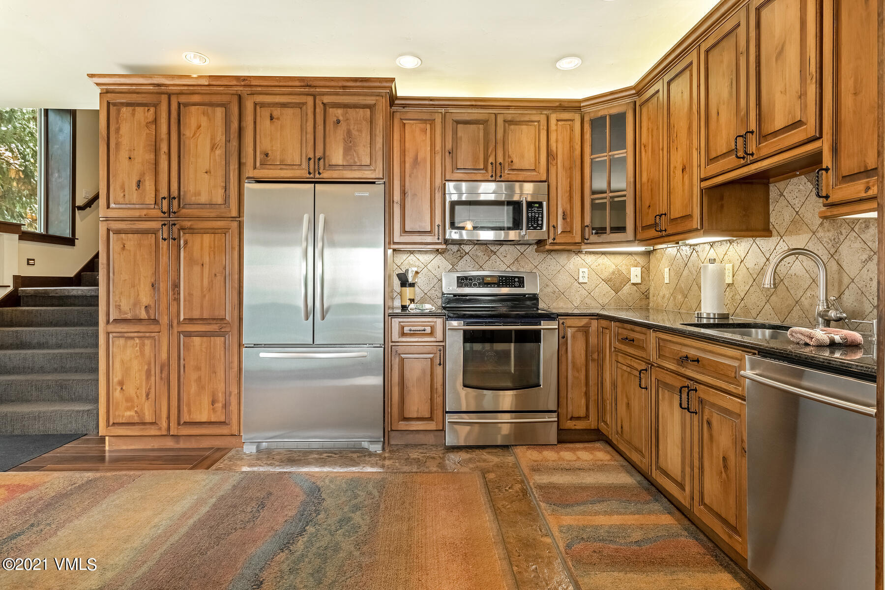 a kitchen with stainless steel appliances granite countertop a refrigerator stove and sink